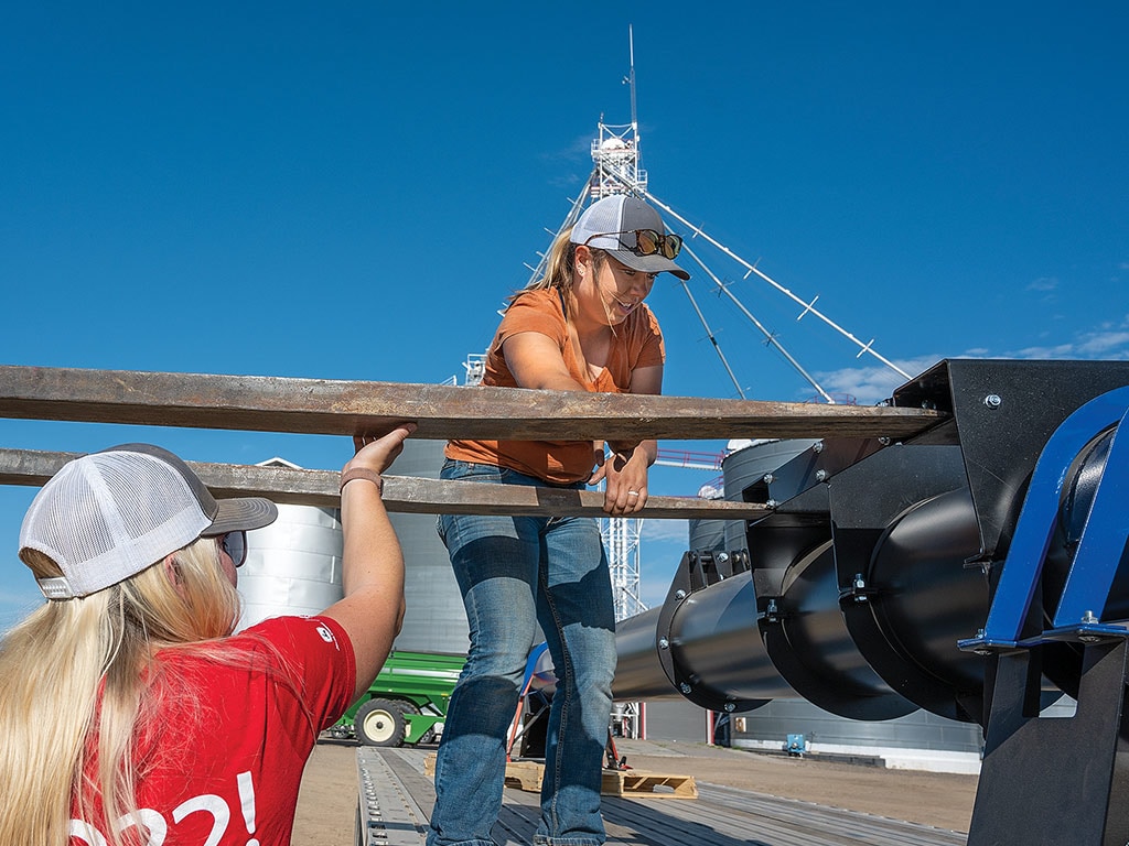 two people on a boat lining up fork lift tines with a pallet