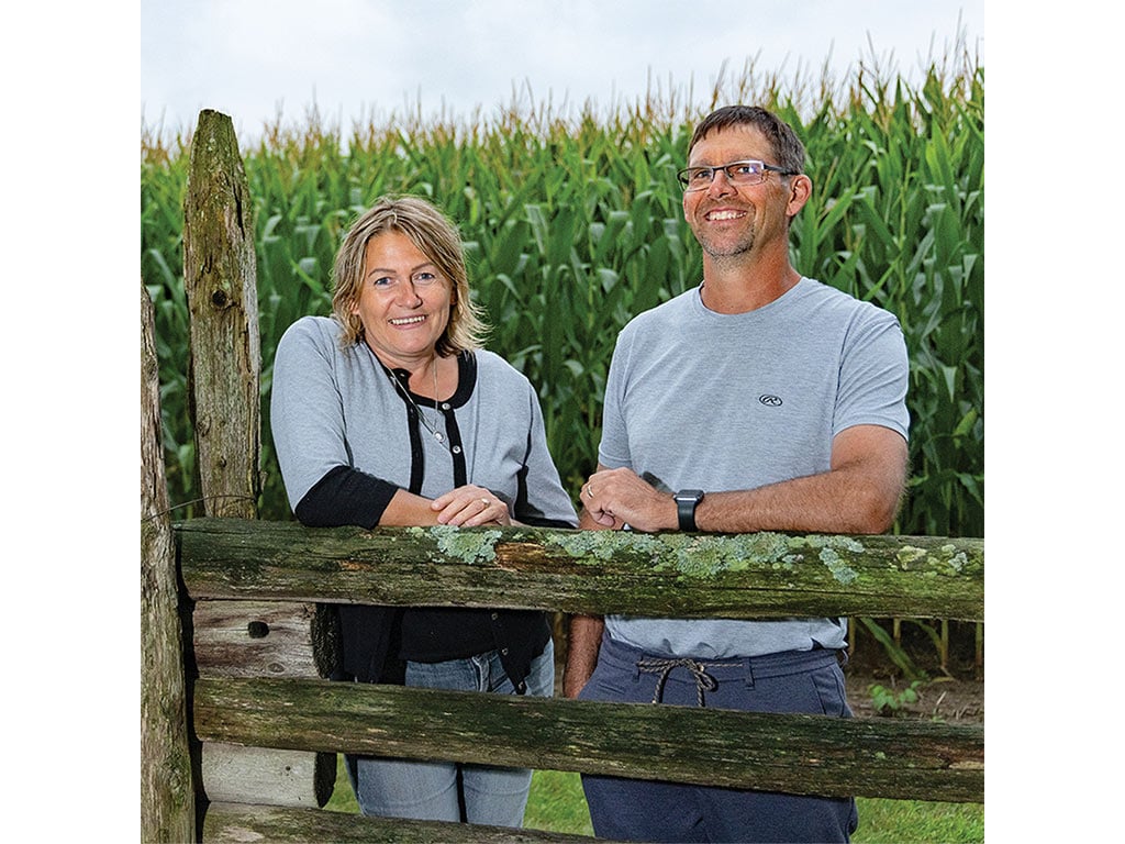 Deux personnes s’appuyant sur une clôture devant des épis de maïs
