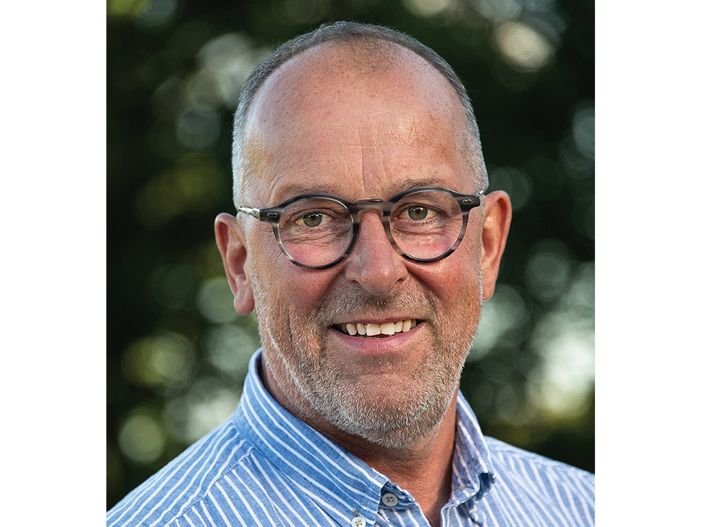 Personne souriante portant des lunettes et une chemise bleu et blanc