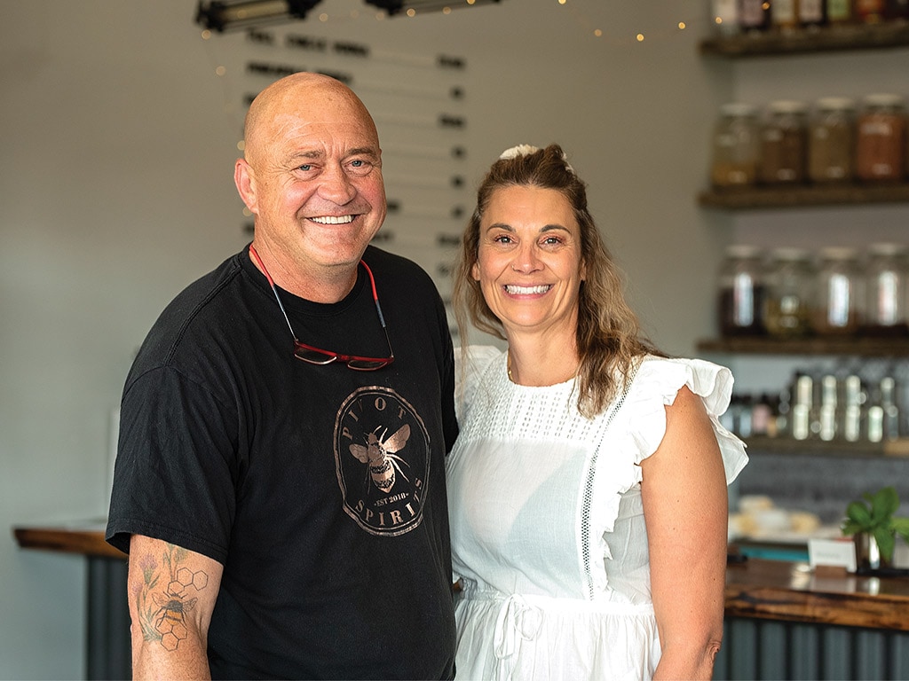 couple souriant pour une séance photo à l’intérieur de la distillerie