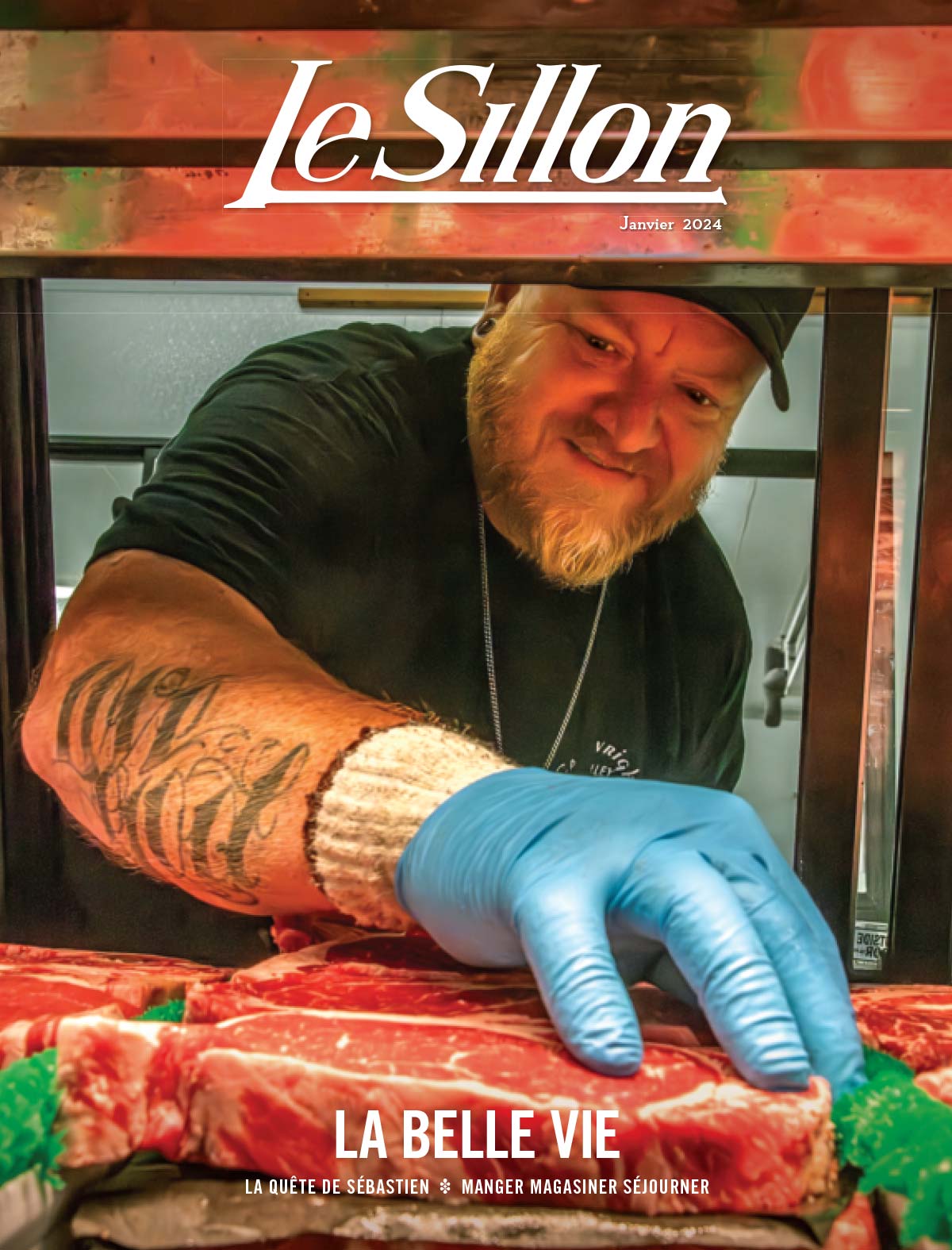 chef cuisinier portant la barbe, une casquette de baseball noire, des tatouages sur les avant-bras et des gants en nitrile bleu pâle qui inspecte un steak dans une cuisine