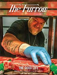 a chef with tattooed arm and light blue latex glove on inspecting a steak