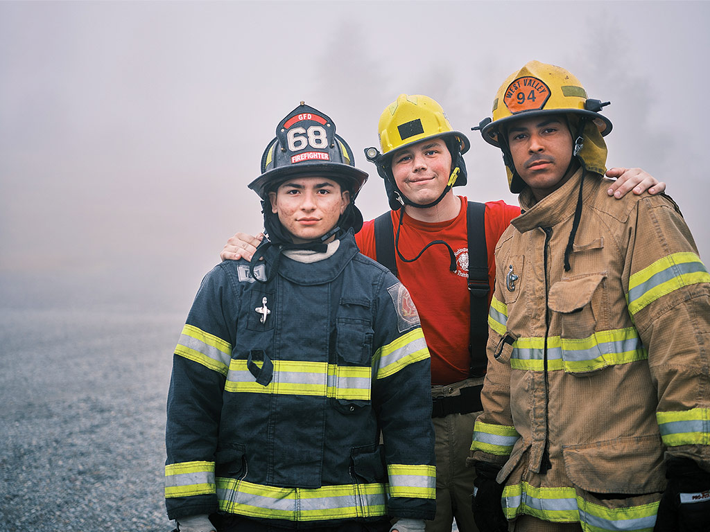 Trois pompiers volontaires en uniforme entourés de fumée