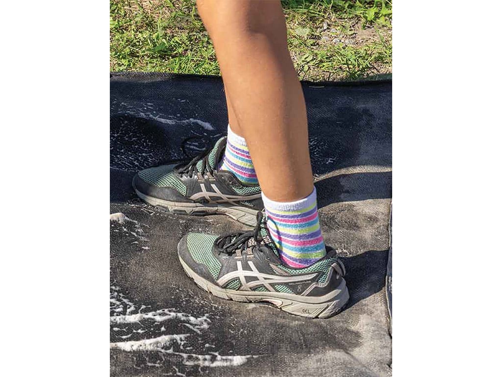 closeup of person's lower legs walking through a disinfectant bath