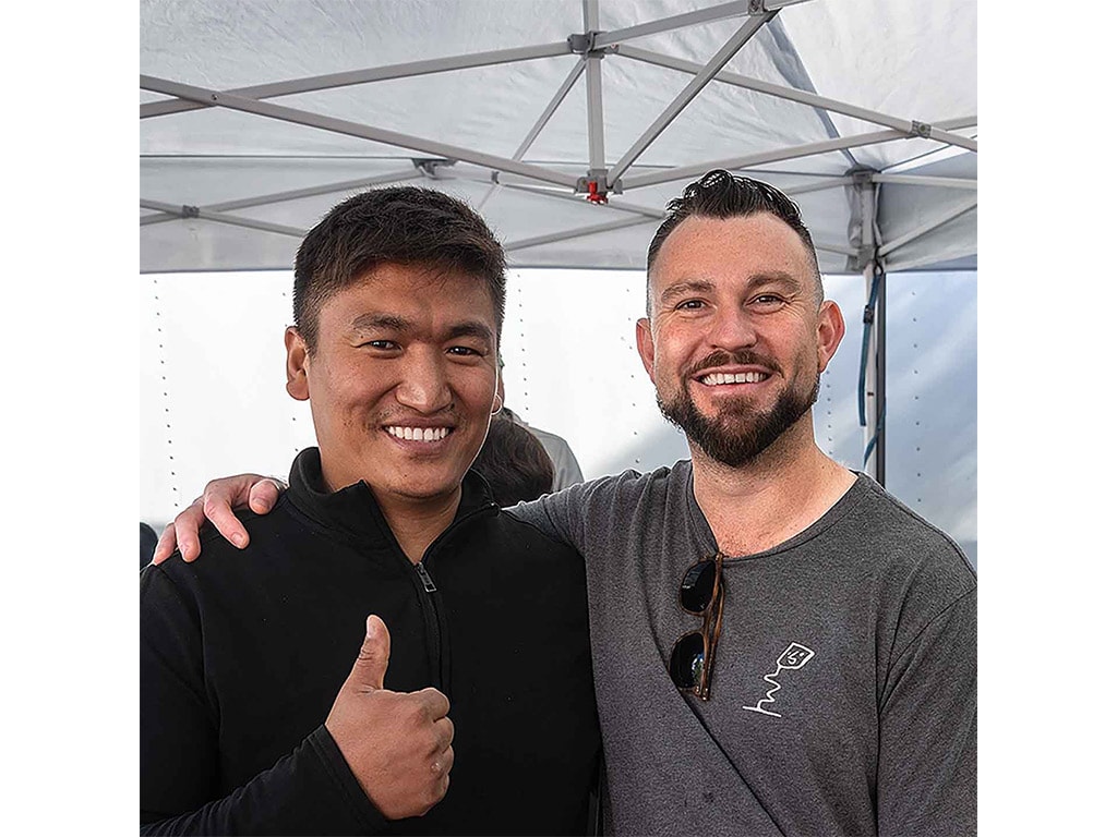 two people smiling with one of them with a thumbs up