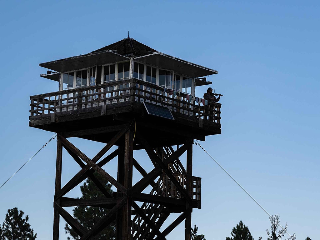 Fire lookout with pine trees and blue sky behind
