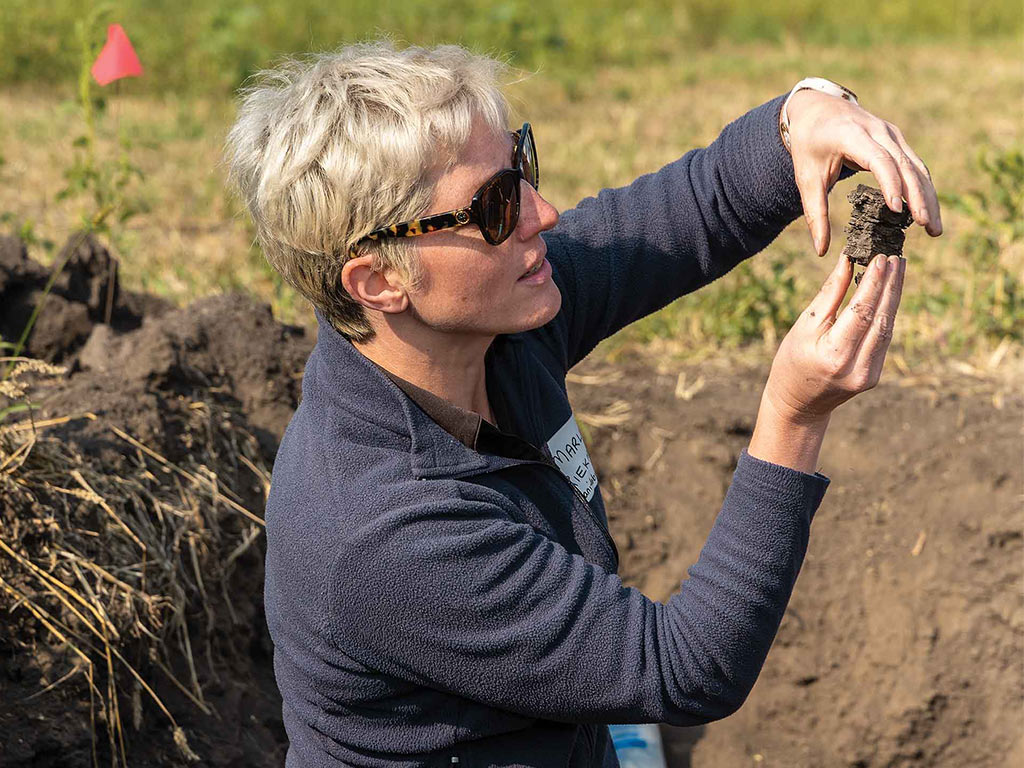 Person with sunglasses inspecting a chunk of dirt