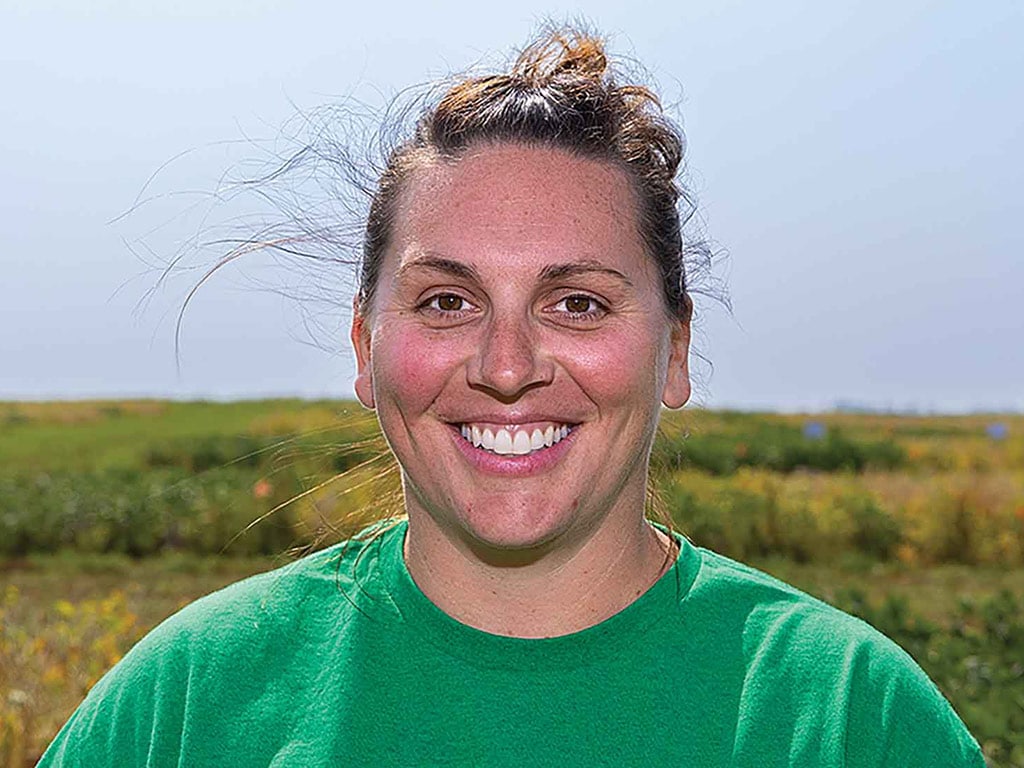 person in green tshirt smiling in a field