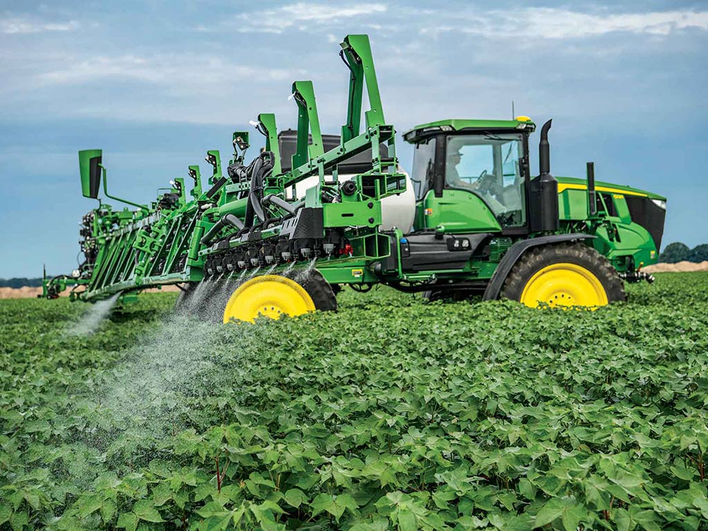 John Deere tractor spraying a field of crops