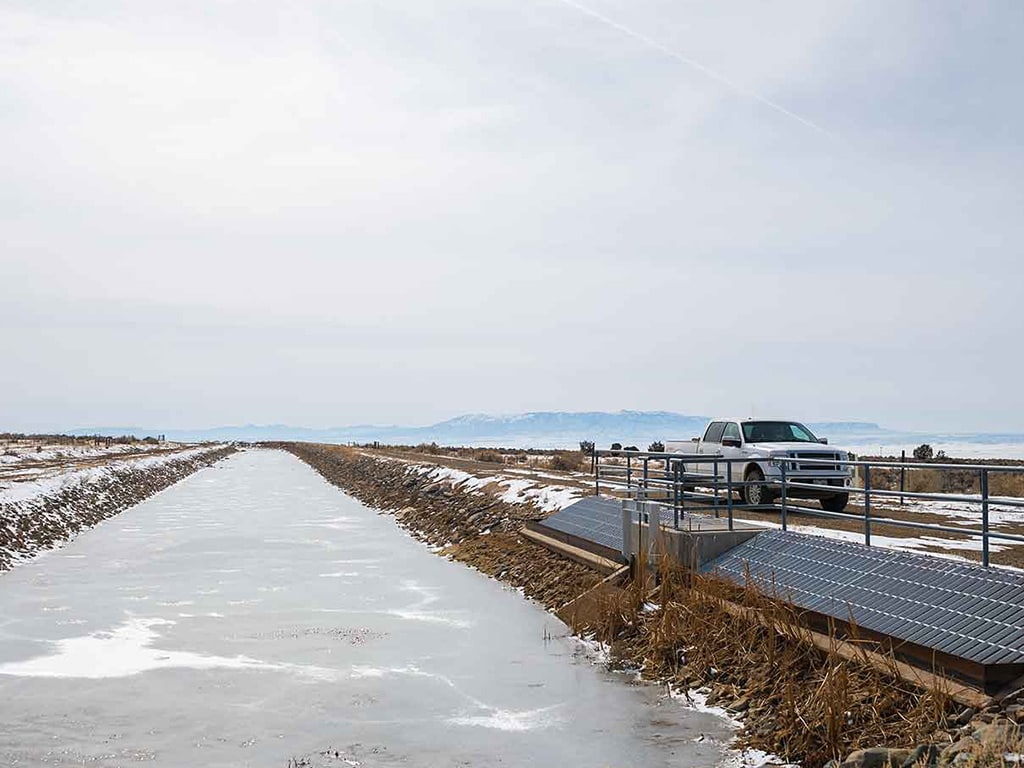 Panorama of frozen canal with pickup truck on a road on the right