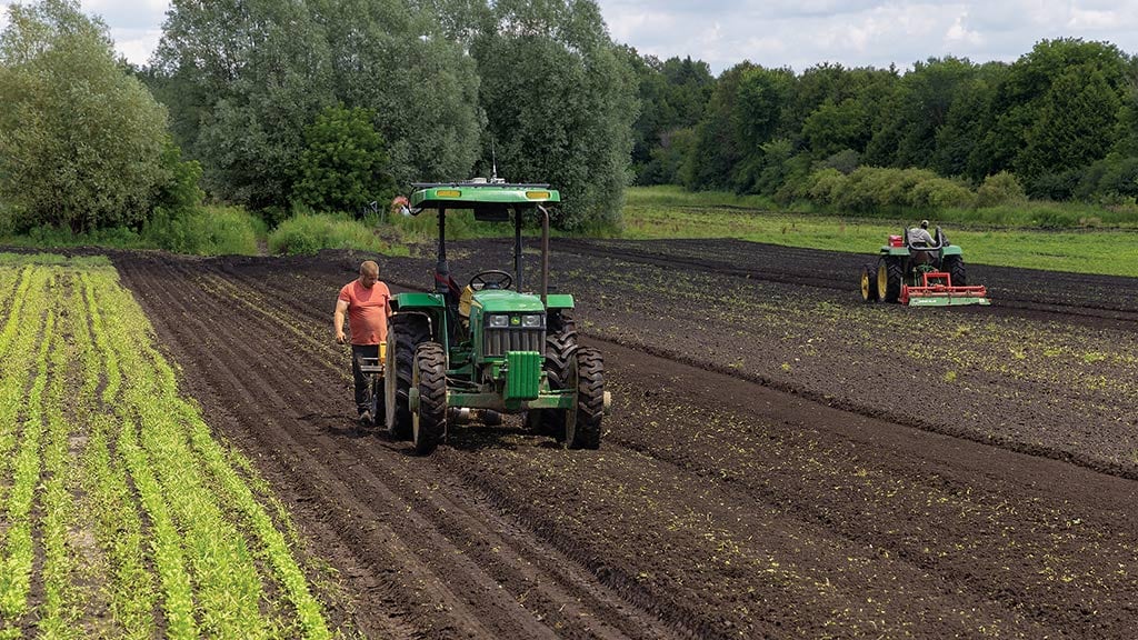 a partially harvested field with a John Deere tractor and a person standing next to it.