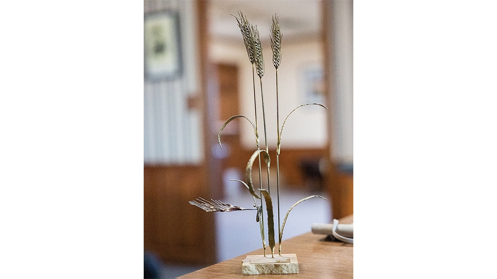 sculpture représentant trois tiges de blé avec une base de roche plate sur une table
