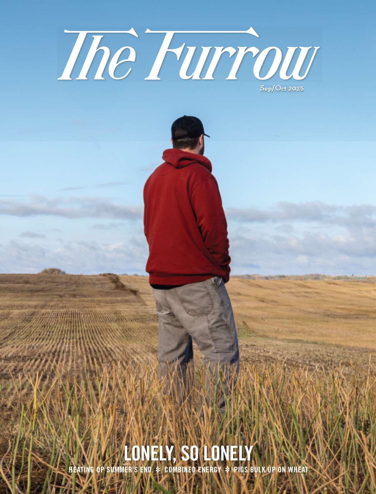 Person in red hoodie and cap in harvested field under blue sky, cover of The Furrow magazine.