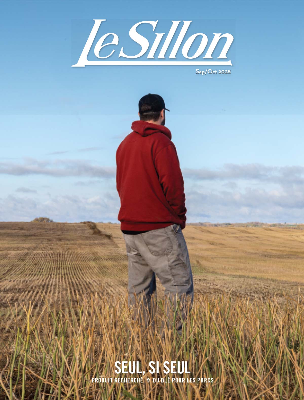 Homme en sweat à capuche rouge et casquette dans le champ récolté sous le ciel bleu, couverture du magazine The Furrow.