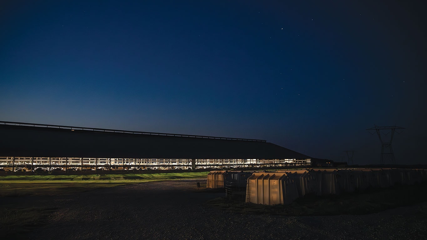 Grande ferme laiti&egrave;re illumin&eacute;e la nuit sous un ciel &eacute;toil&eacute;