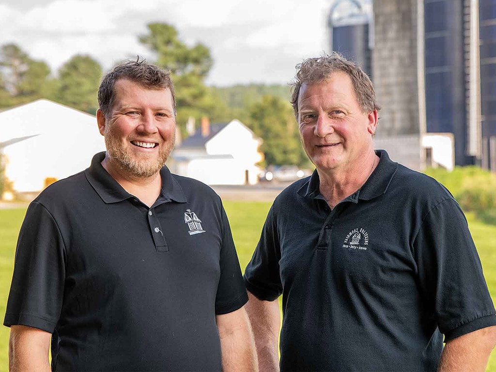 Two people smiling in front of farm yard