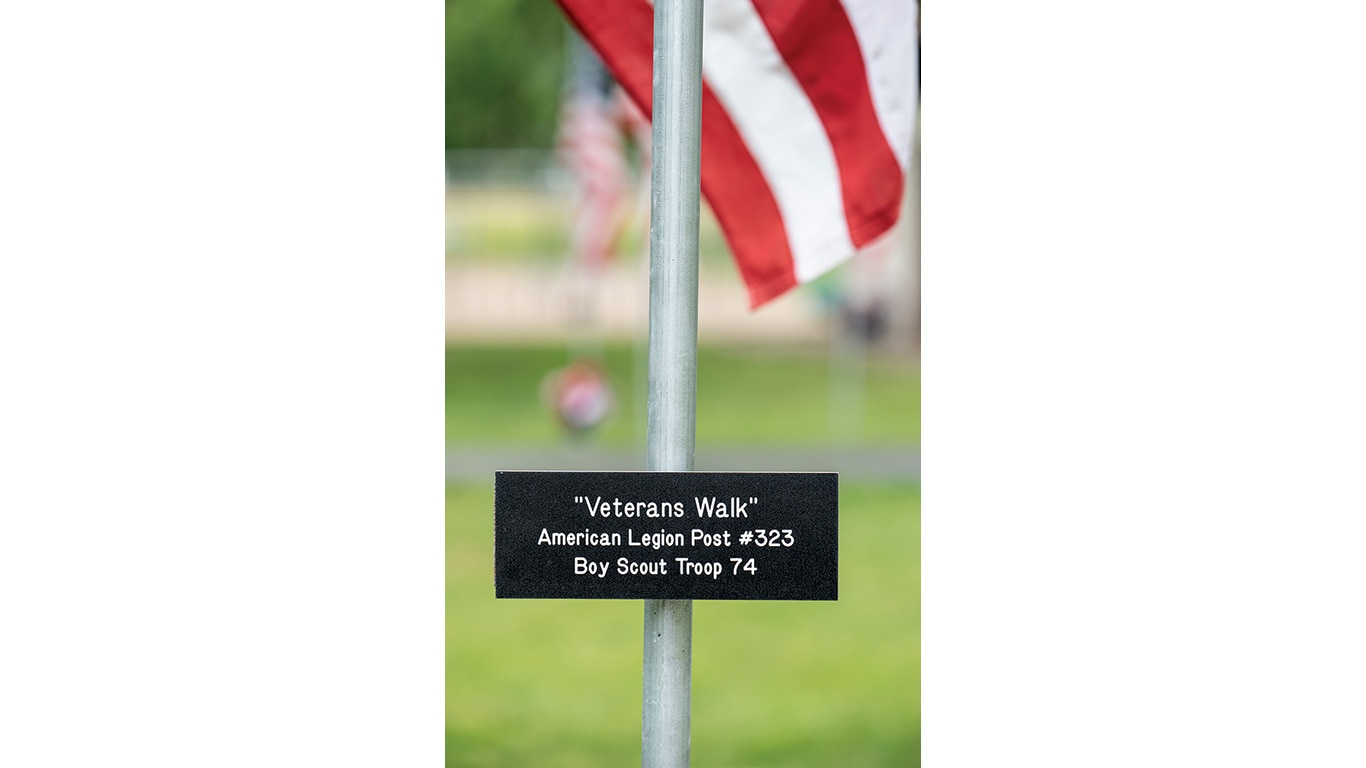 Sign on a pole reads "Veterans Walk" with American flags in the background.