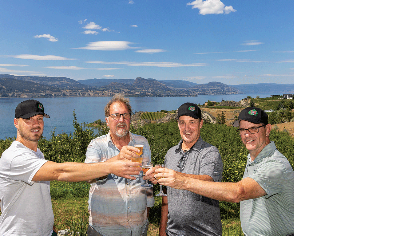 Quatre personnes l&egrave;vent leurs verres ensemble &agrave; l'ext&eacute;rieur, avec un lac et des collines en arri&egrave;re-plan.