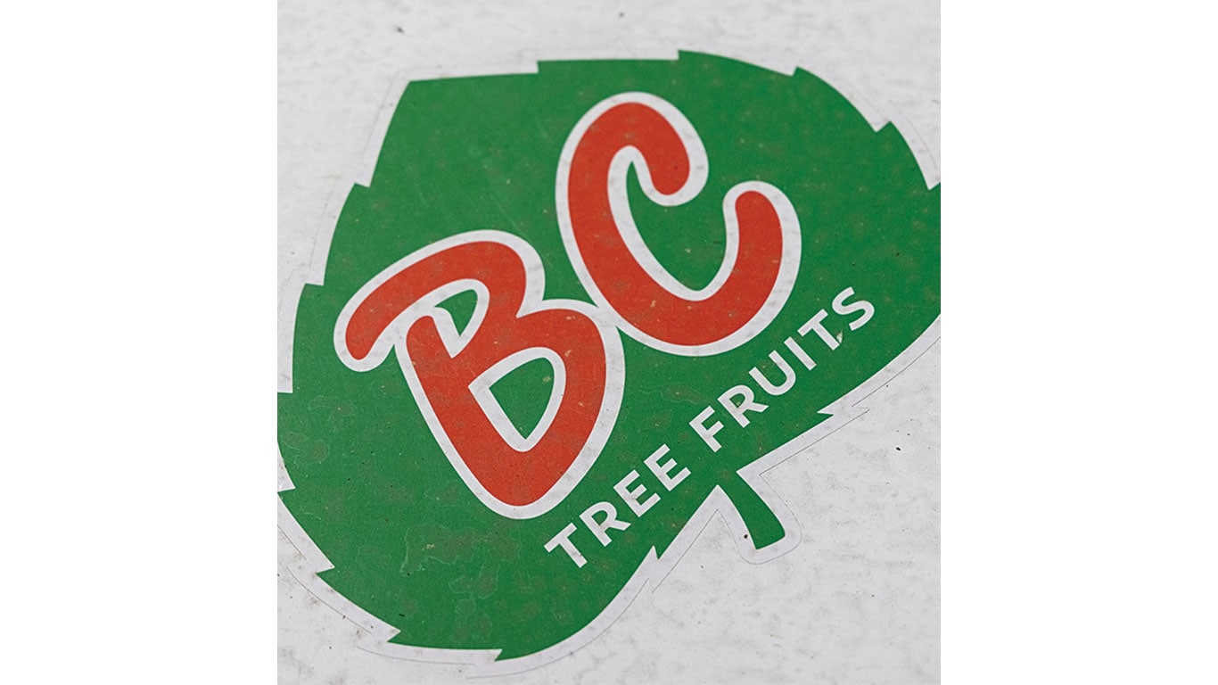 Logo de BC Tree Fruits sur une enseigne verte en forme de feuille.