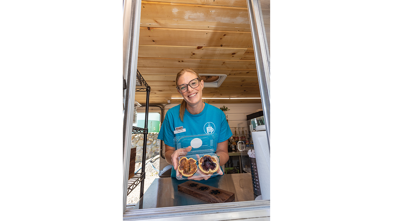 Woman holding butter tarts in a plastic container.