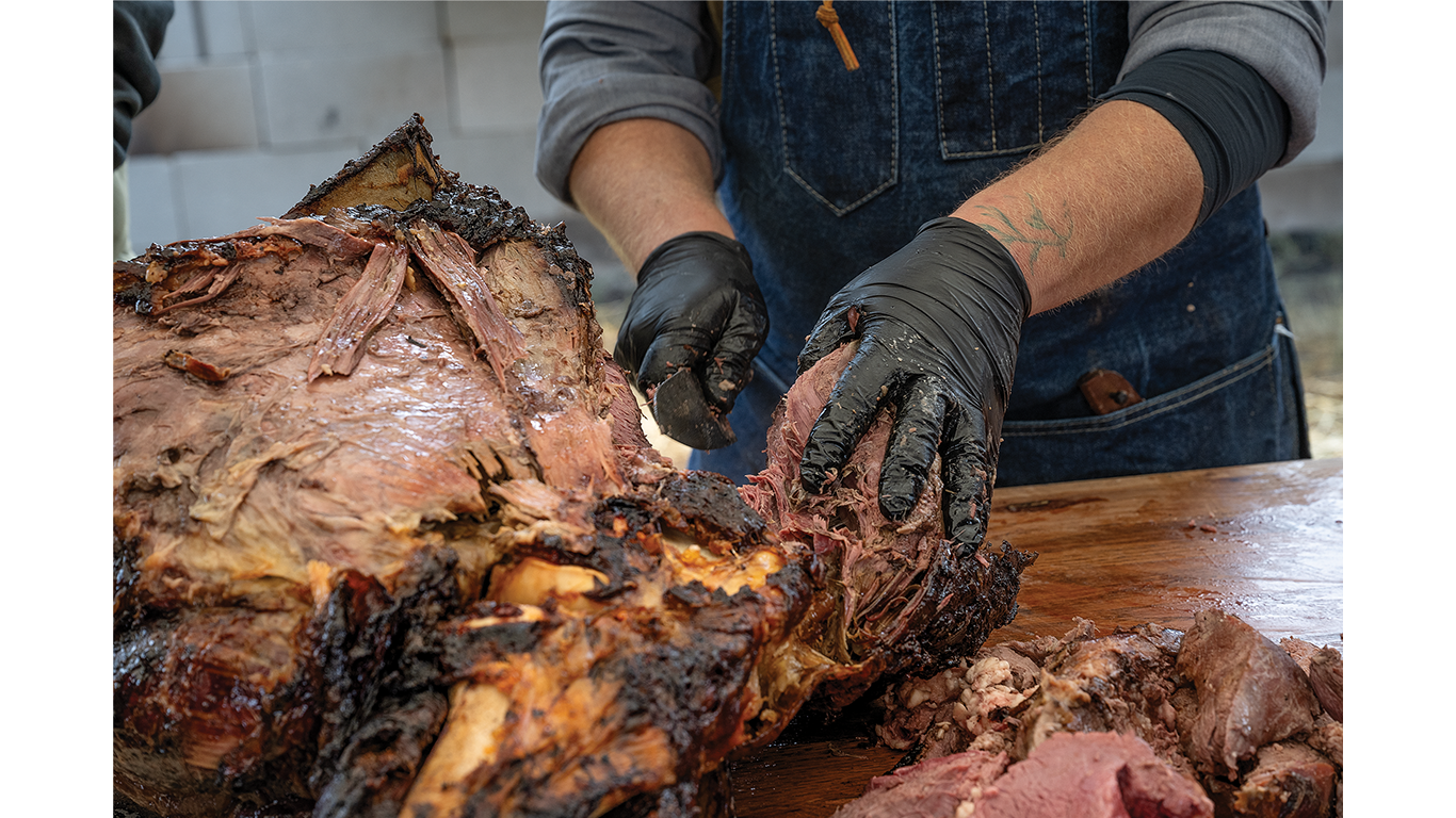 Person with gloves pulling and shredding beef.