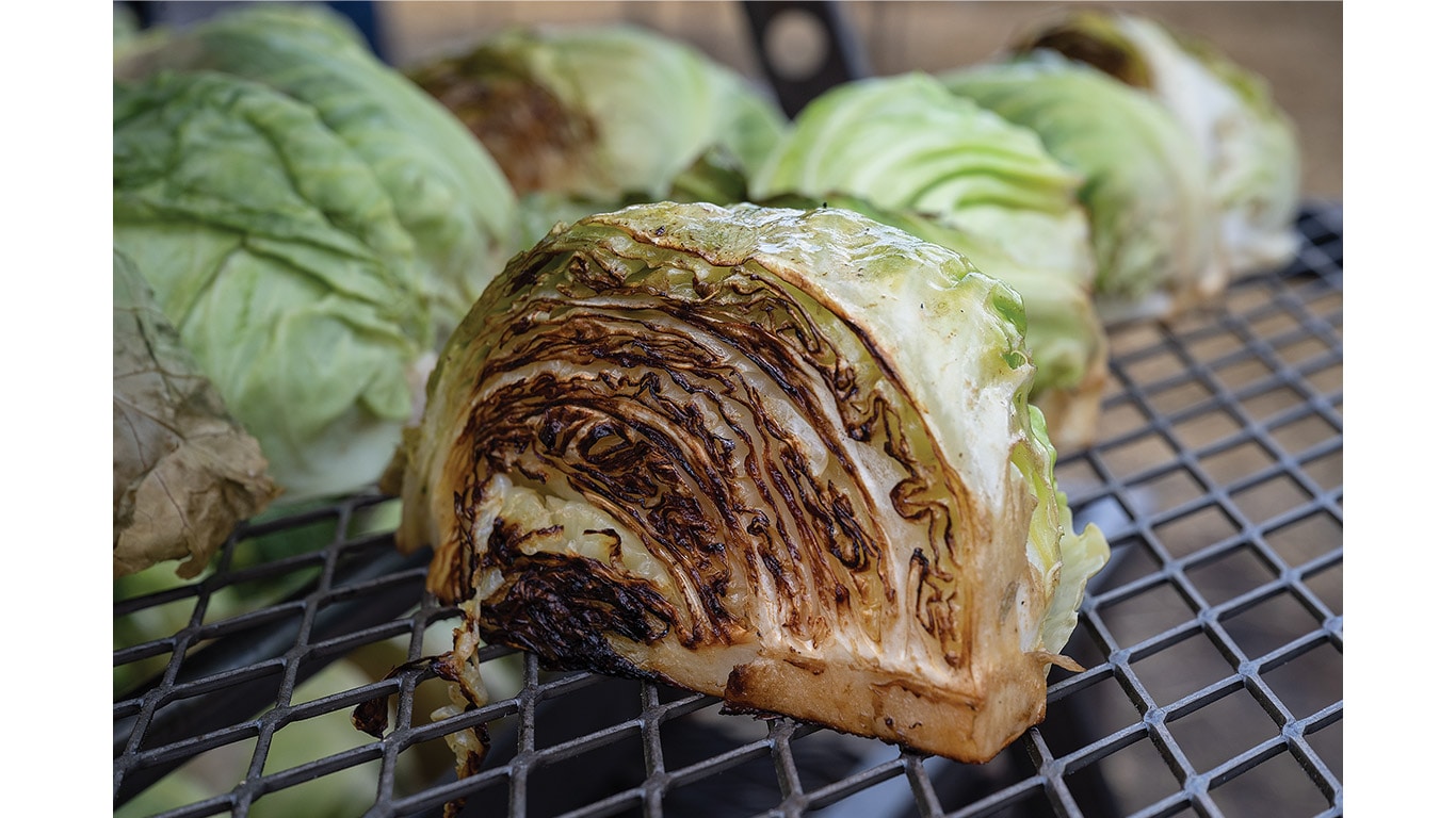 Grilled cabbage wedges resting on a metal cooking grate.