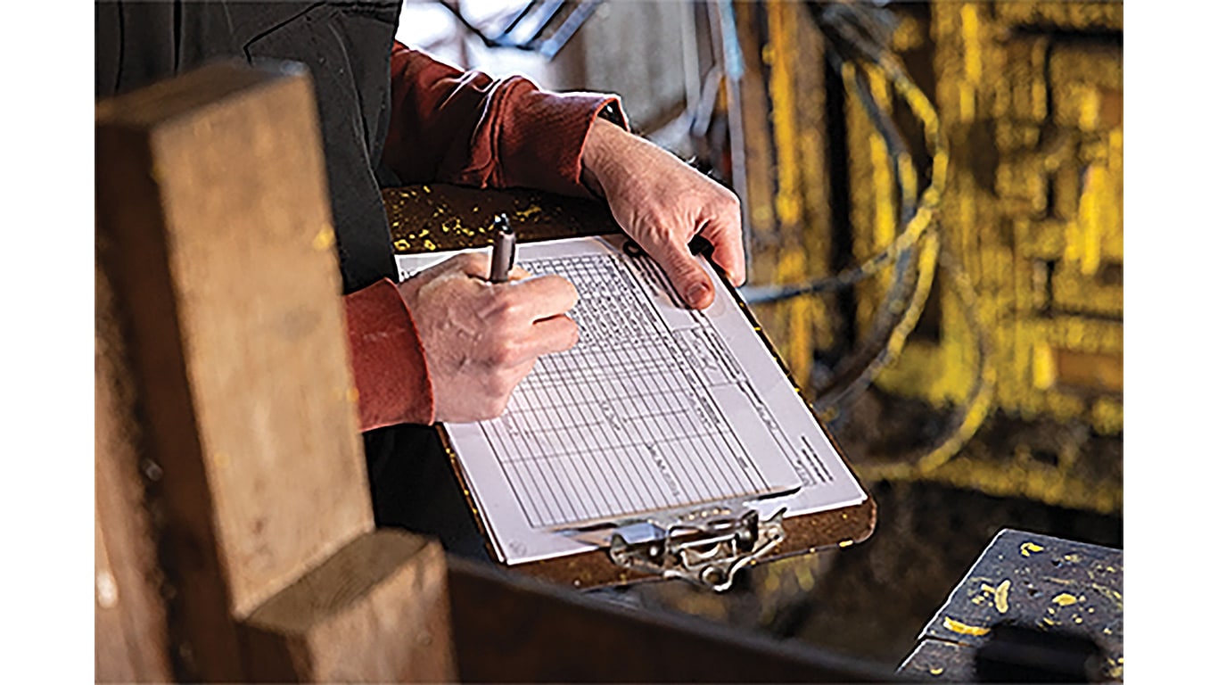 Hands holding clipboard and writing down information with a pen.