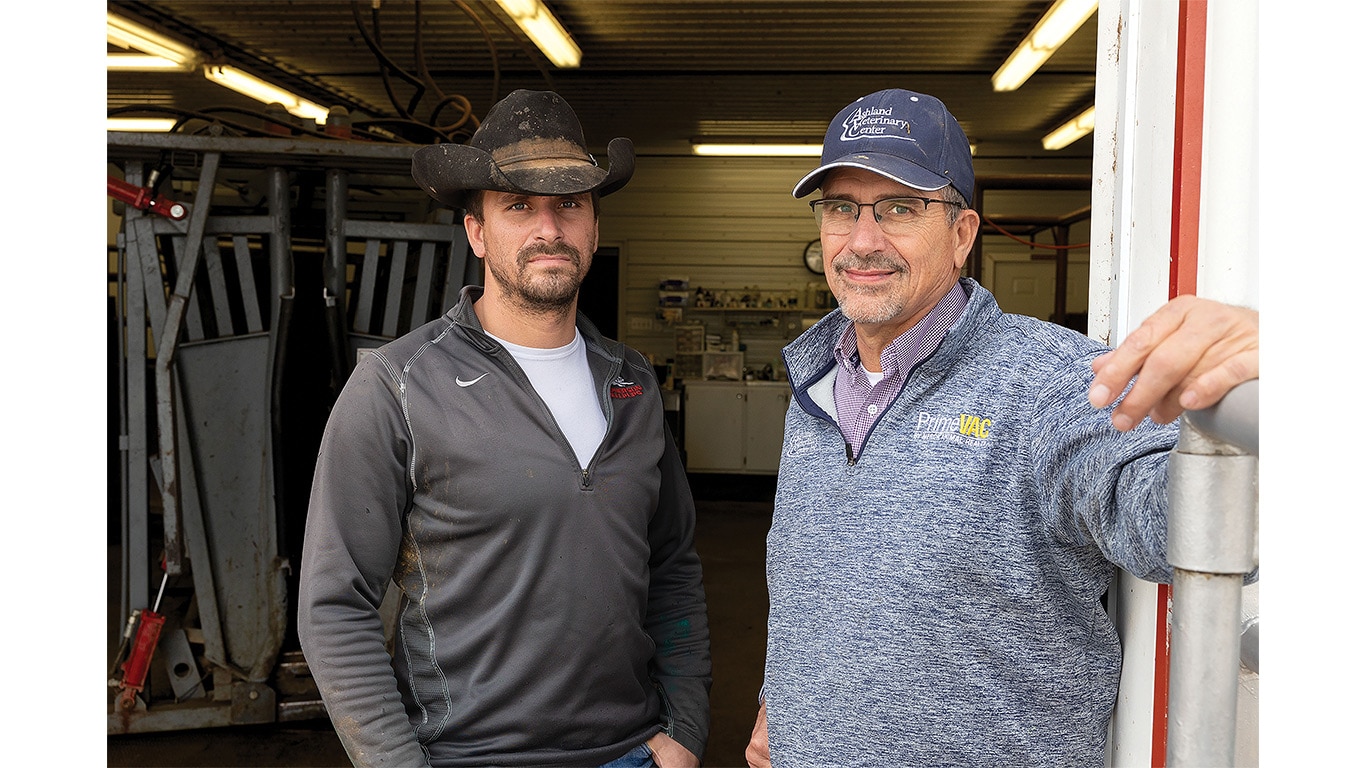 Two individuals, one with a cowboy hat and the other with a ball cap, standing in a doorway.