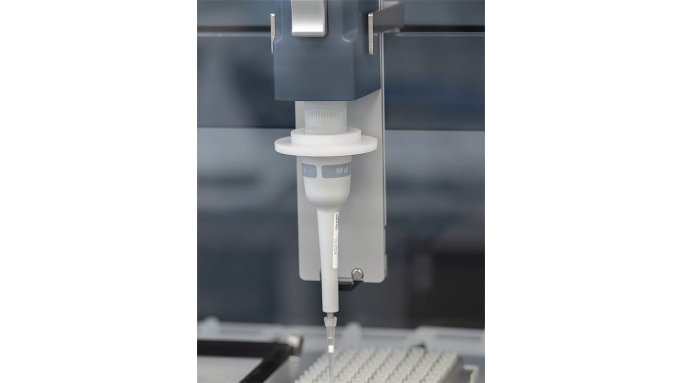 Automated pipetting instrument dispensing liquid into a lab tray.