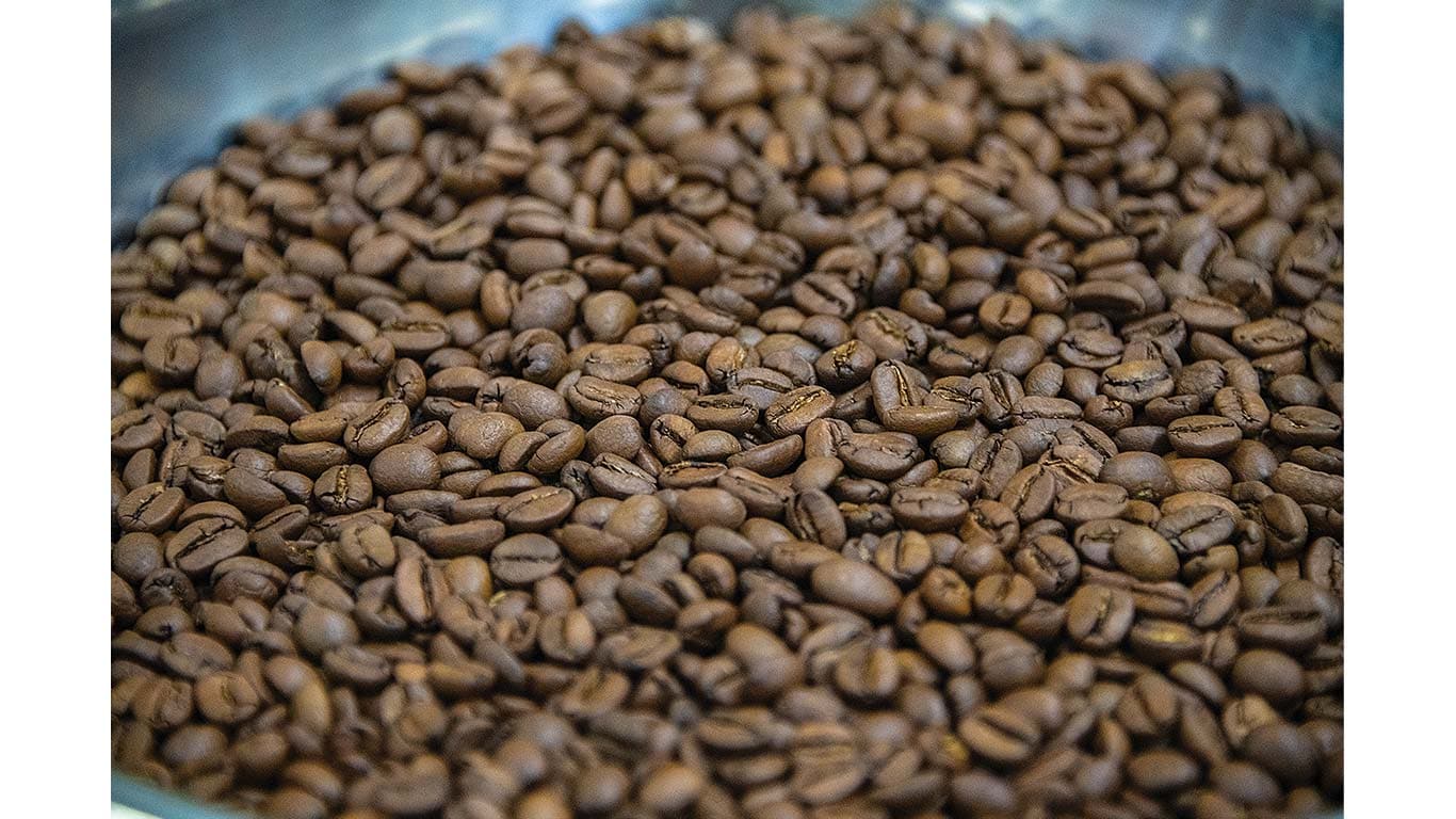 Close-up of roasted coffee beans piled in a metal container.