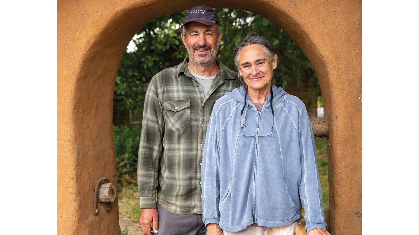 Two people standing together under a rustic outdoor archway.