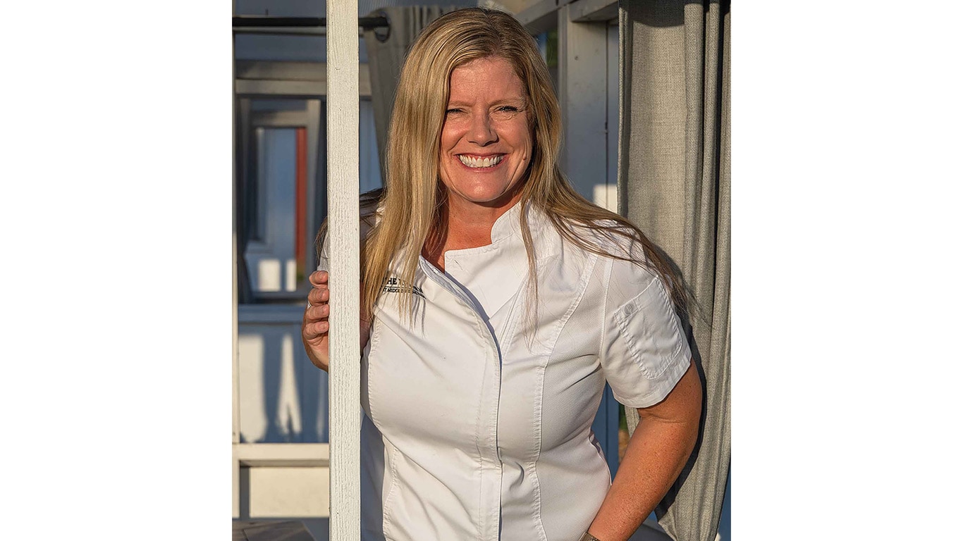 Person in a white chef coat standing in a doorway.