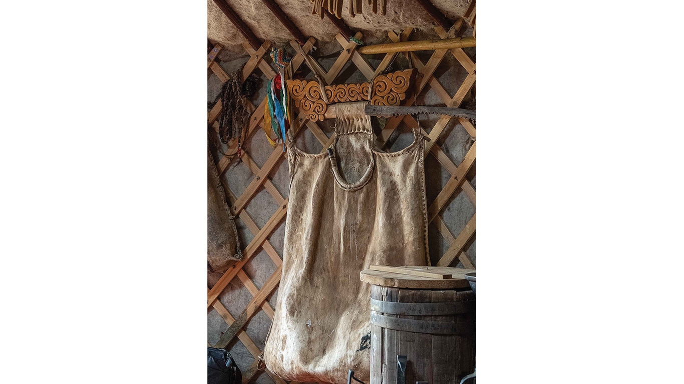 A traditional felt garment hanging inside a wooden lattice‑framed yurt.