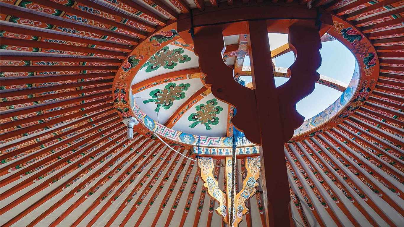 Decorated wooden roof structure inside a traditional yurt.