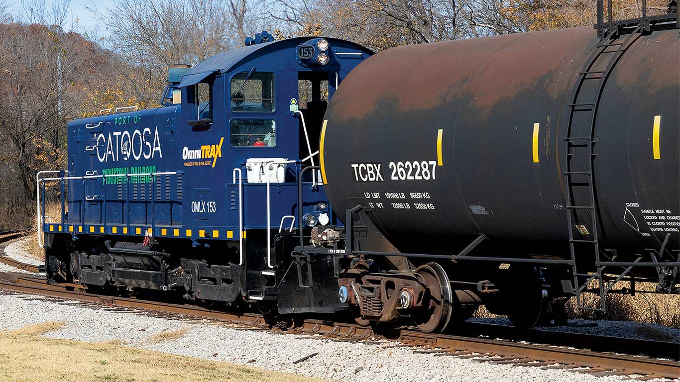 Un train bleu avec un wagon-citerne fix&eacute; sur les voies ferr&eacute;es.