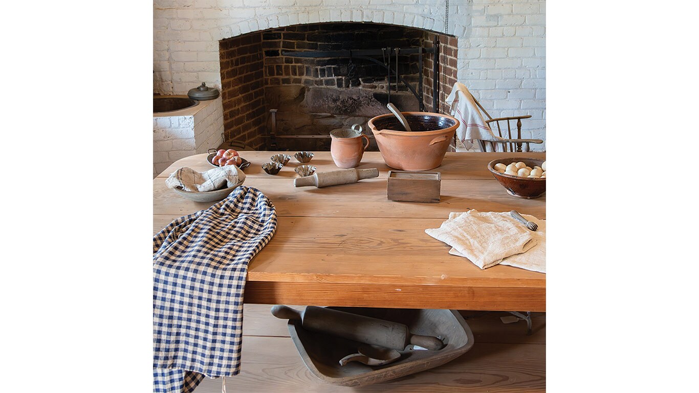 Wooden table with baking tools and ingredients set in front of a brick fireplace.