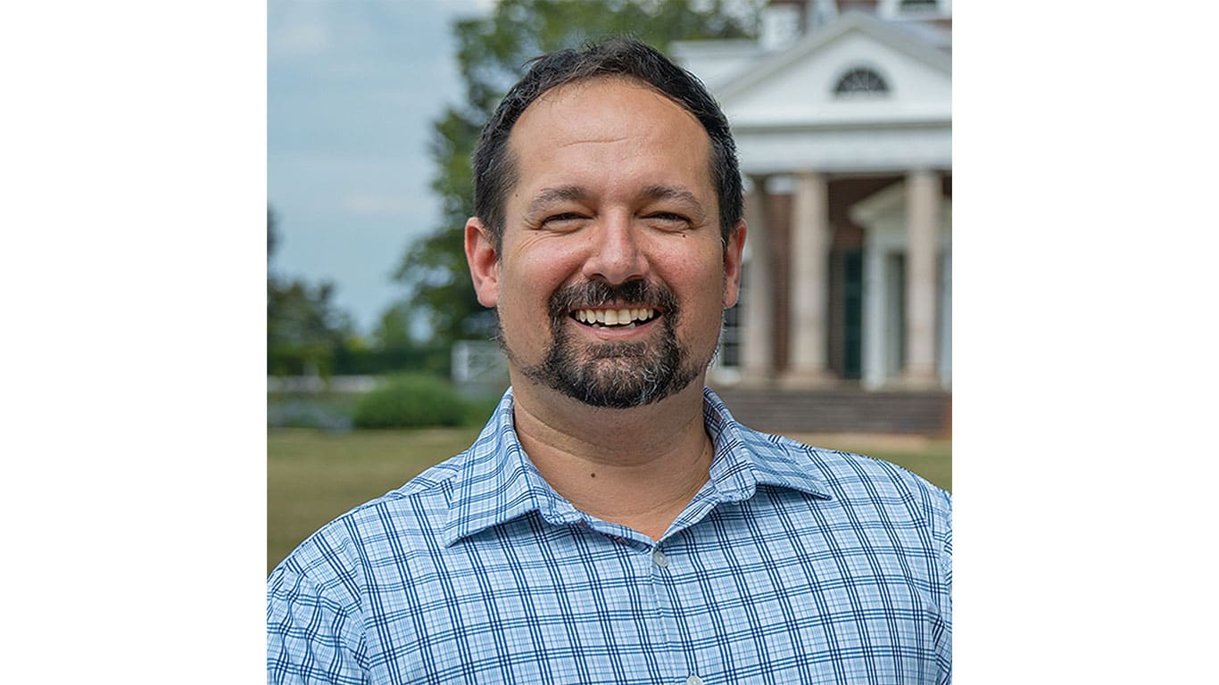 A person standing outdoors with a columned building in the background.
