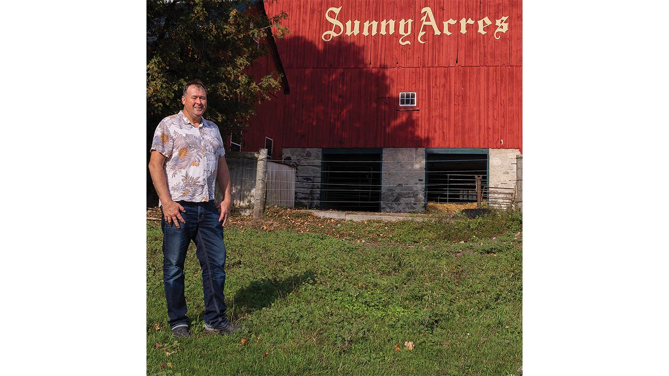 Person standing in front of a red barn labeled "Sunny Acres."