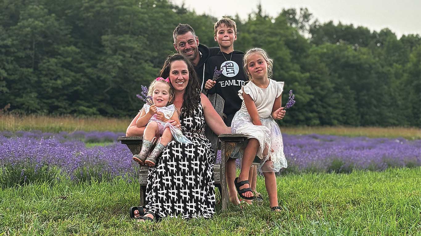 Groupe de personnes assises et debout dans un champ de lavande tenant des fleurs.