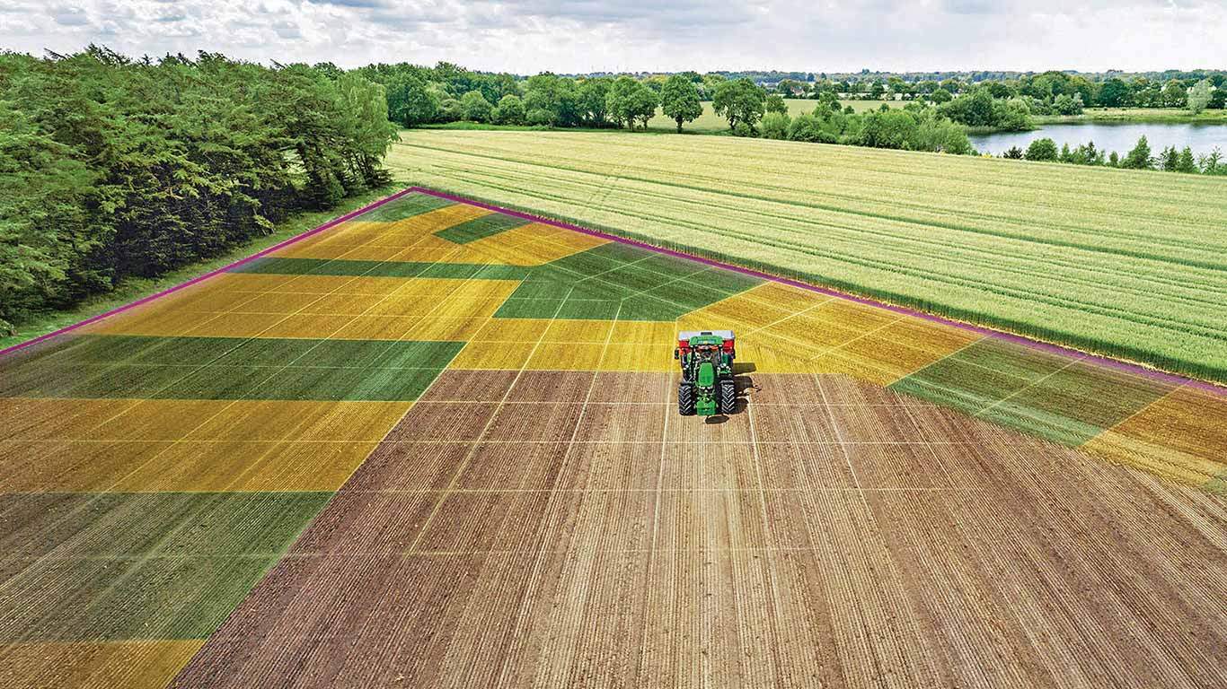 Vue aérienne d'une mosaïque de champs de cultures avec un tracteur au centre et différentes parcelles autour.