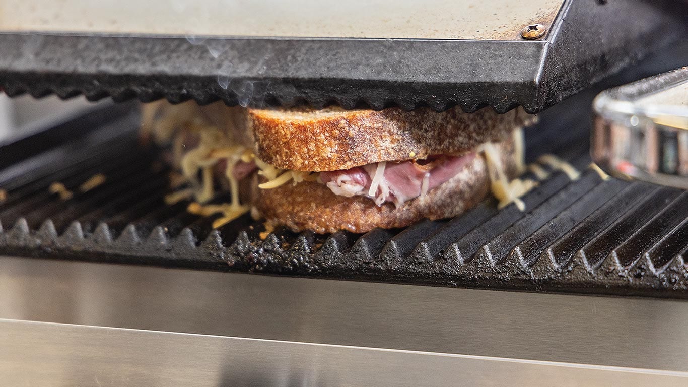 Un sandwich à récurer sur une calandre est enfoncé pour ajouter des marques de calandre des deux côtés du pain.